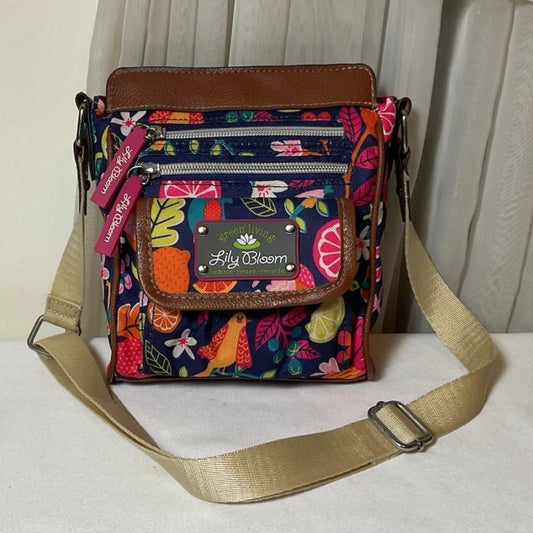 Colorful crossbody bag with floral pattern and visible brand label on a white surface.